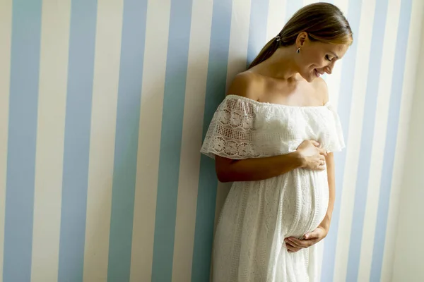 部屋の壁のそばに立ってかなり若い妊婦 — ストック写真