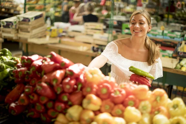 市場で新鮮な野菜を買うのはかなり若い女性 — ストック写真