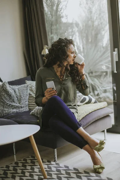 Lockigt Hår Ung Kvinna Med Hjälp Mobiltelefon Och Innehav Mugg — Stockfoto