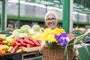 Piyasada satın alma ve sepet çiçekli tutan kadın kıdemli portresi