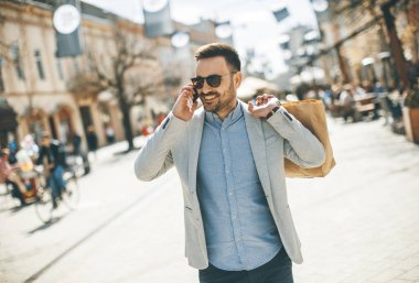Neşeli yakışıklı adam portresi kullandığı cep telefonu ise şehirde alışveriş gidiyor
