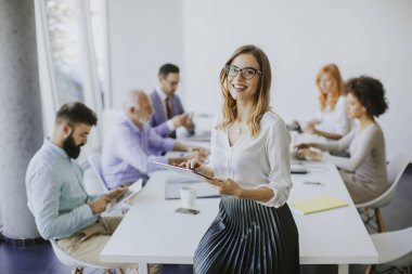 Genç çekici kadın Yöneticisi duran modern Office dijital tablet üzerinde çalışan
