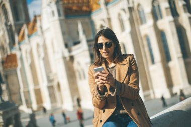 Açık ve kullanma cep telefonu oturan trendy genç kadın görüntüleme