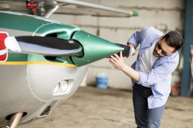 Yakışıklı genç pilot hangarda uçak kontrol