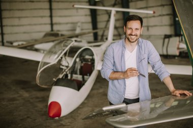 Yakışıklı genç pilot hangarda uçak kontrol