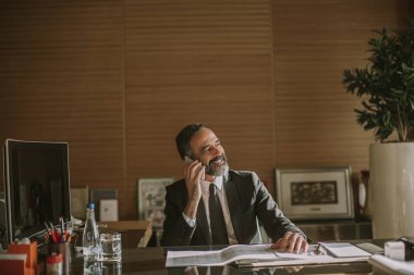 Mobila telefon kullanarak ve modern ofisinde çalışan üst düzey işadamı portresi