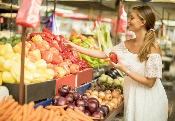 市場で新鮮な野菜を買うのはかなり若い女性 — ストック写真