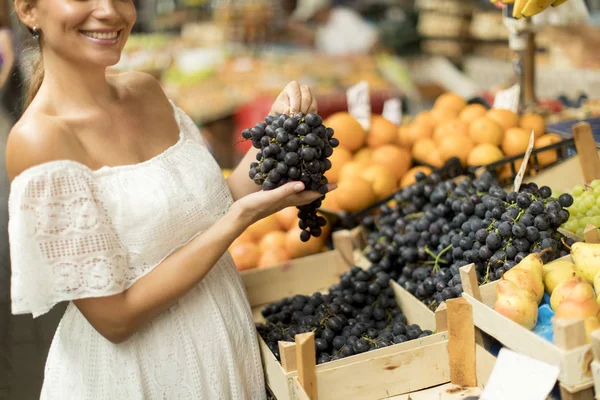 市場で新鮮な果物を買うのはかなり若い女性 — ストック写真
