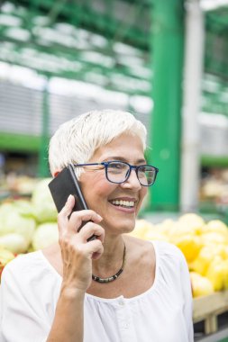Sebze pazarında satın alma ve cep telefonu kullanarak kadın kıdemli portresi