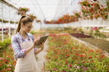 Tablet yeşil bahçesinde kullanan genç kadın portresi