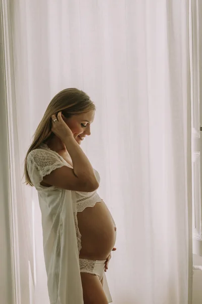 Ganska Ung Gravid Kvinna Som Står Vid Fönstret — Stockfoto