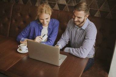 Restoran içinde laptop ile tablo başına oturmuş ve online alışveriş yaparken genç Çift