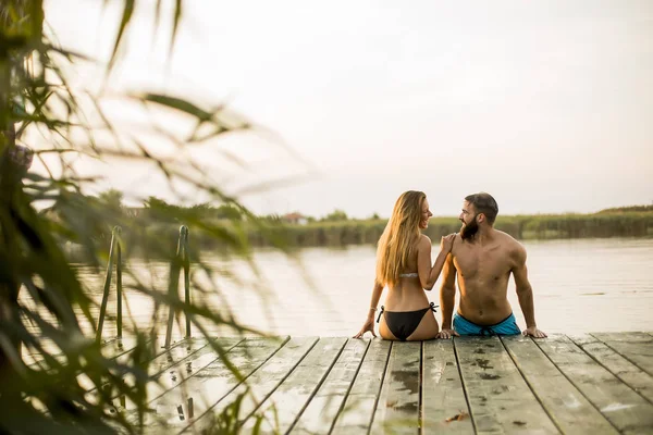 Couple at wooden pier on river at hot summer day