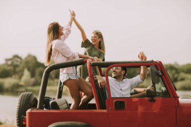 Mutlu arkadaşlar eğlenmeye Cabrio araba tatil nehir kenarında