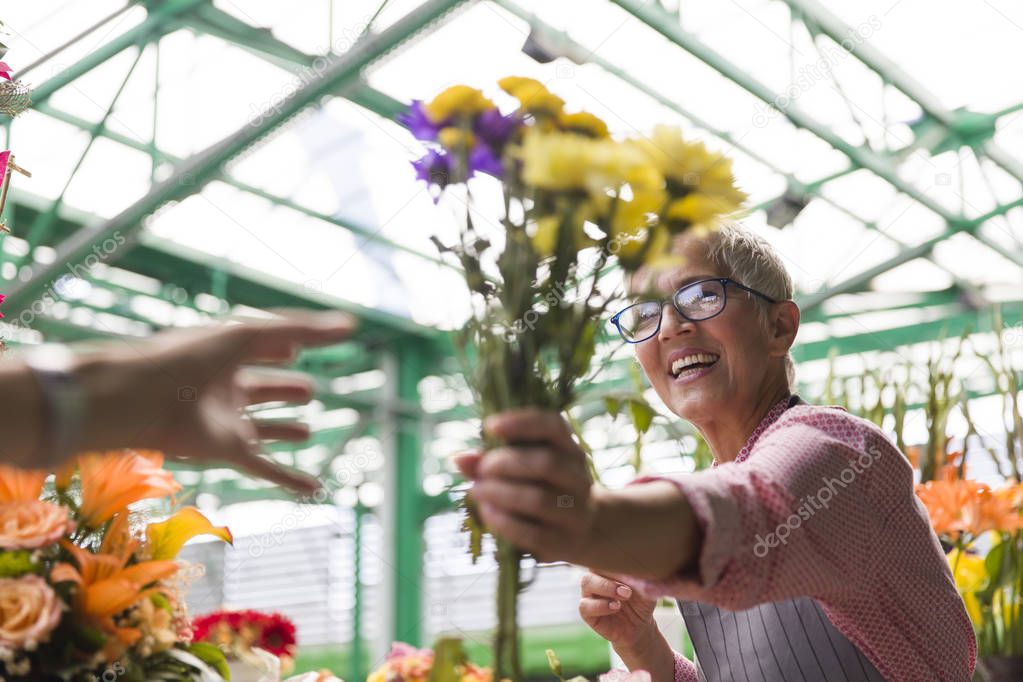Charrming senior woman sales flowers on local market