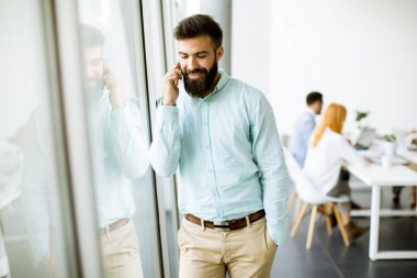 Genç işadamı Office diğer insanlar bir toplantıyı yapmak arka planda iken cep telefonunuzu kullanarak