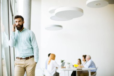 Genç işadamı Office diğer insanlar bir toplantıyı yapmak arka planda iken cep telefonunuzu kullanarak