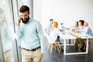 Genç işadamı Office diğer insanlar bir toplantıyı yapmak arka planda iken cep telefonunuzu kullanarak