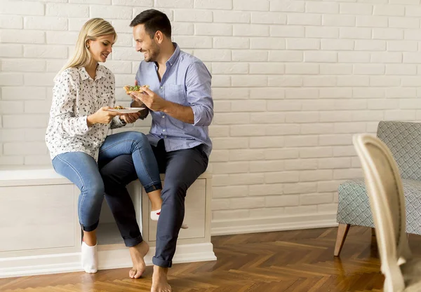 Lovely young couple eating pizza in the room