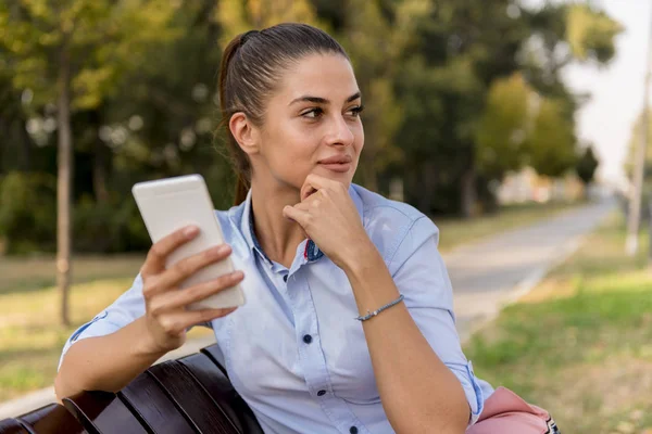 公園で携帯電話を使用しての若い女性の肖像画 — ストック写真