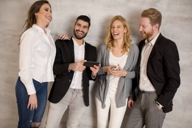 Gençlerin grup birlikte duvar arka plan üzerinde duran ve cep telefonuyla iyi görünümlü