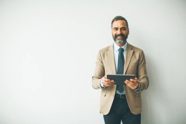 Beyaz duvar tarafından dijital tablet ile yakışıklı üst düzey işadamı portresi