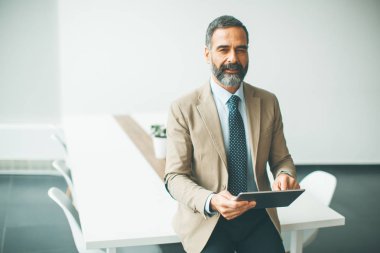 Ofiste dijital tablet ile yakışıklı olgun işadamı portresi