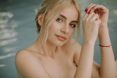 Genç ve güzel sarışın kadın rahatlatıcı ve havuz kenarı