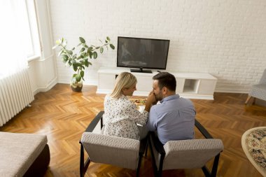 Oturma odasında televizyon izleyen çiftin dikiz görüntüsü