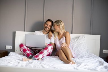 Seven çift yatakta evde dizüstü bilgisayar ile