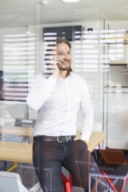 Modern ofiste onun akıllı telefon kullanan mutlu genç adam