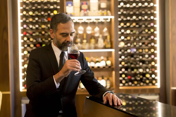 Handsome mature man tasting glass of red wine