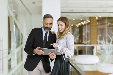 Genç işkadını ve işadamı dijital tablet üzerinde bakmak ve modern ofis yeni proje hakkında tartışmak