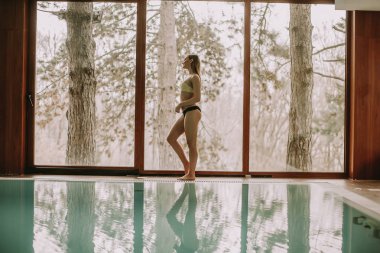 Yüzme havuzunun kenarında yürüyen genç ve güzel kadın