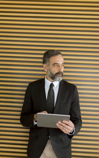 Handsome middle age businessman with digital tablet in the modern office