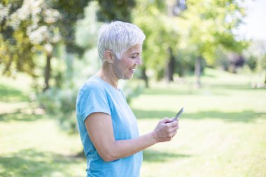 Akıllı telefon açık kullanarak giyim spor kadın kıdemli portresi