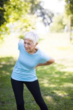 Sırtının alt kasların sürtünme kıdemli fitness kadın. Sırt ağrısı