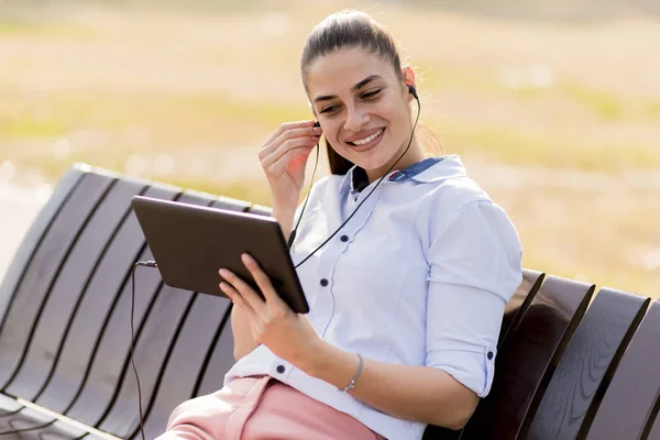 Mujer Joven Sentada Banco Parque Escuchar Música Una Tableta — Foto de Stock