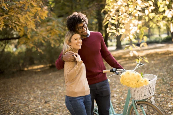 年轻的多种族夫妇在公园里散步 推着自行车 — 图库照片