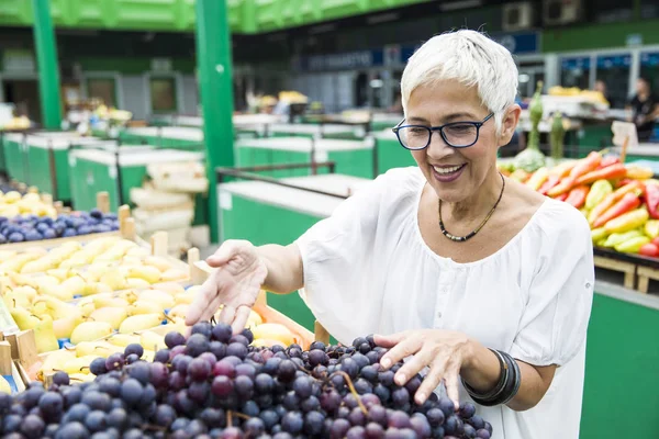 Seniorin Wählt Auf Dem Markt Rote Trauben — Stockfoto