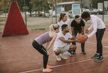 Gençlerin grup sahada basketbol oynarken çok ırklı