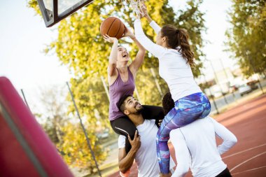 Gençlerin grup sahada basketbol oynarken çok ırklı