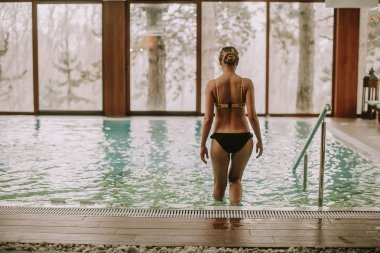 Genç ve güzel kadın su spa Center'da yüzme havuzunda girdiğini