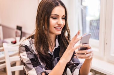 Cep telefonu kafede kullanan genç kadın portresi