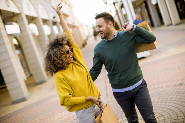 Lovely young multiethnic couple with bags in the shopping