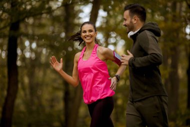 Atletik çift birlikte sonbaharda orman iz üzerinde çalışan