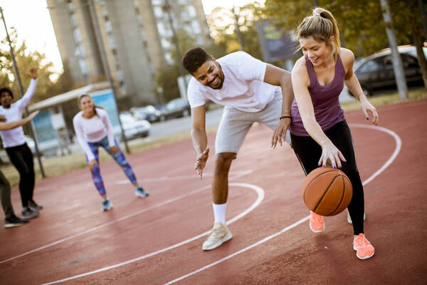 Group of multiethnic young people  playing basketball on court