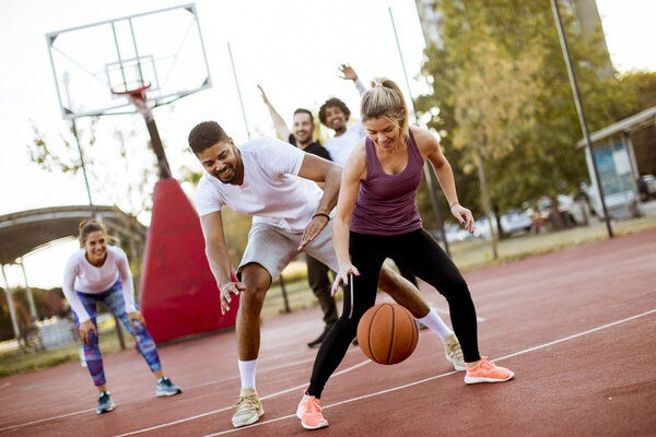 Group of multiethnic young people  playing basketball on court