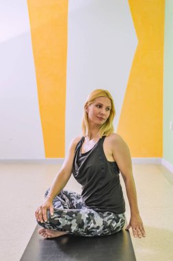 Orta yaş kadın Yoga yoga stüdyosu, bir egzersiz mat yaparken