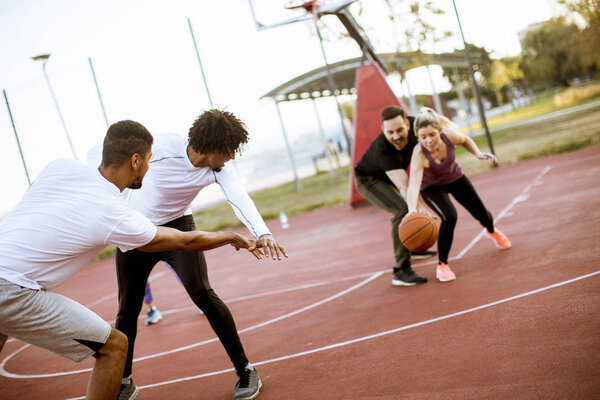 Group of multiethnic young people  playing basketball on court